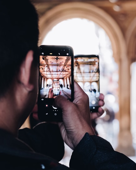 A traveler holding a smartphone displaying interactive content about a historic mosque, smiling as they explore.