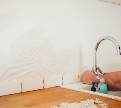 person holding gray curved faucet