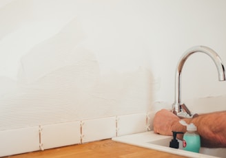 person holding gray curved faucet