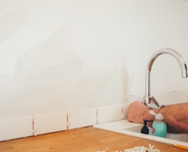 person holding gray curved faucet