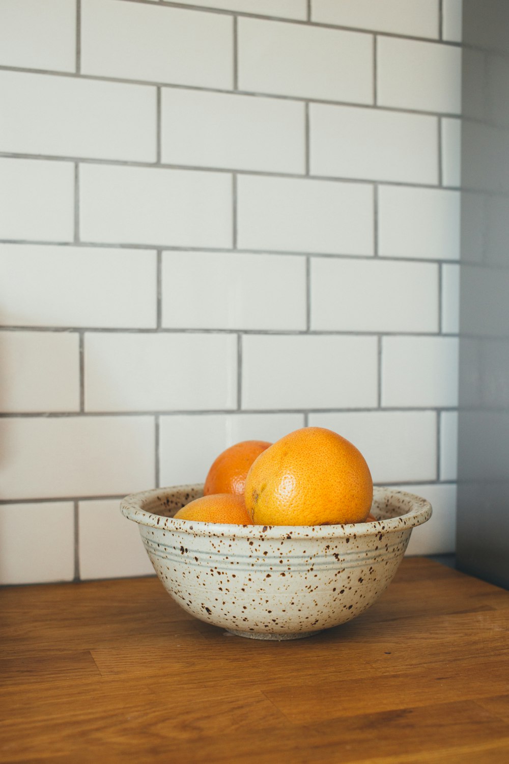 Drei orangefarbene Früchte in weißen Keramikschalen auf dem Tisch