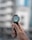 A hand holding a smartwatch with an airplane image displayed on its screen, showing the time as 5:30. The background is blurred, suggesting an urban environment.