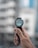 A hand holding a smartwatch with an airplane image displayed on its screen, showing the time as 5:30. The background is blurred, suggesting an urban environment.