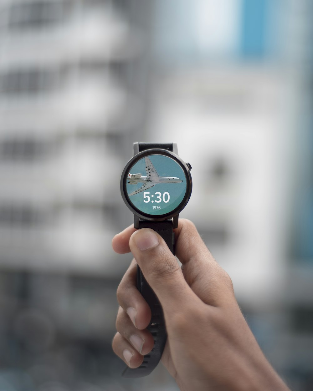 Fotografia de foco seletivo de pessoa segurando smartwatch preto exibindo 5:30