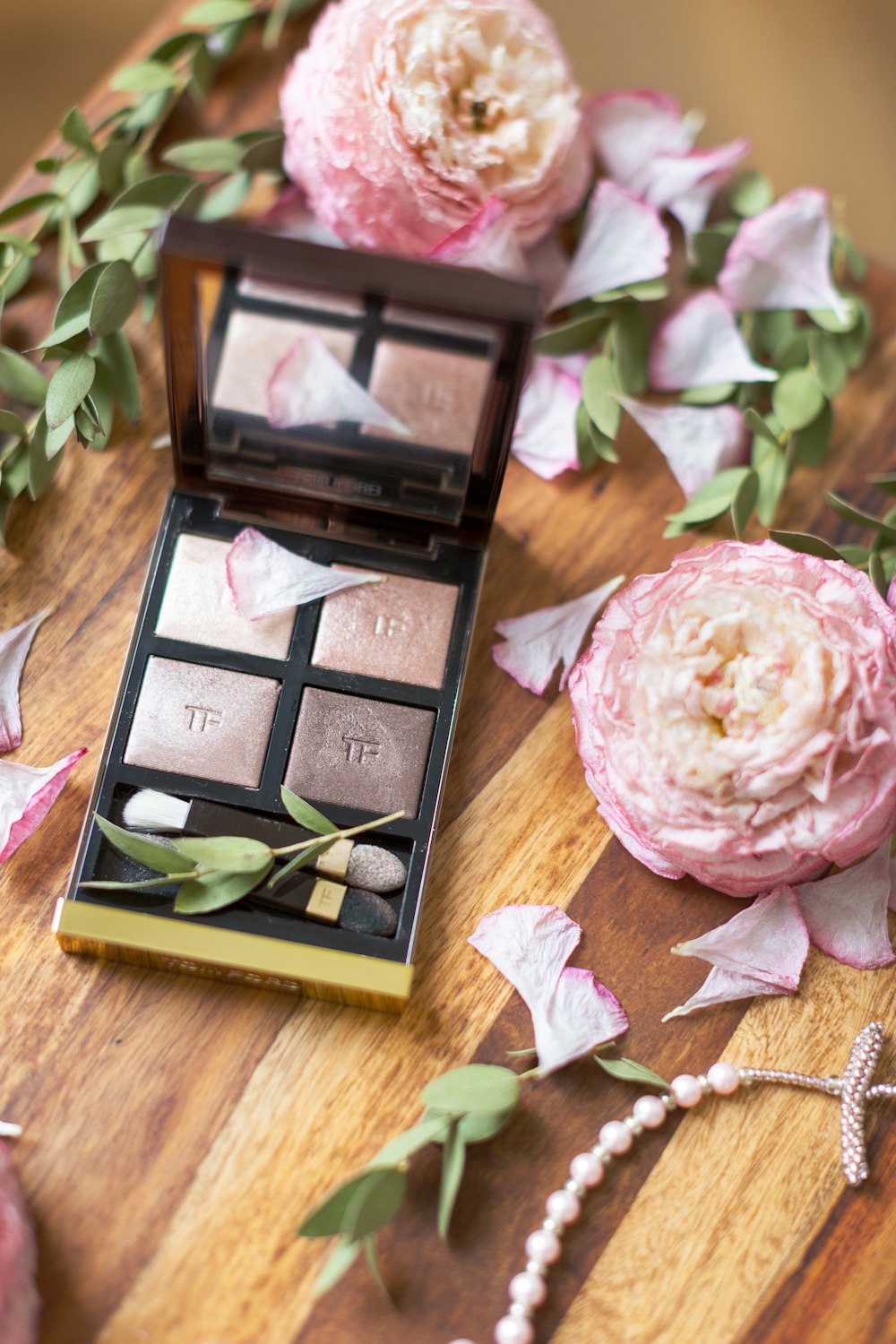 palette de maquillage à côté des fleurs roses