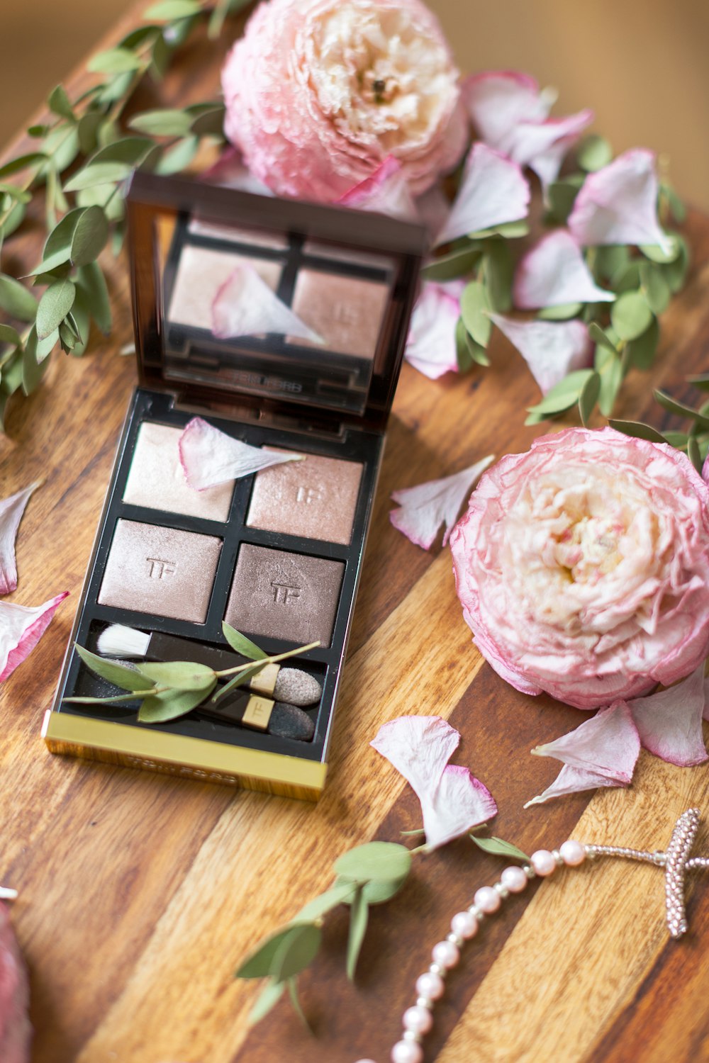 makeup palette beside pink flowers