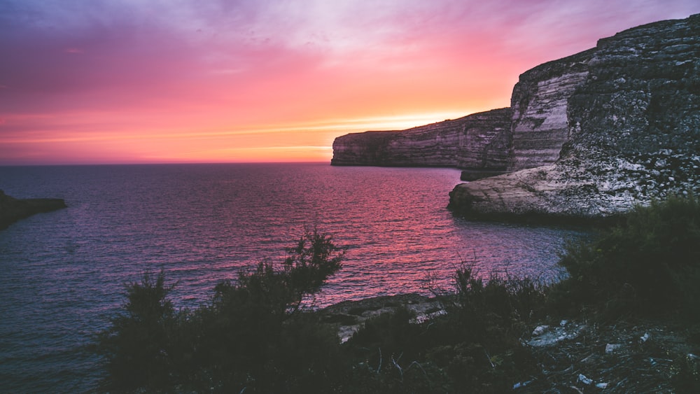 photography of ocean and rock formation at golden hour