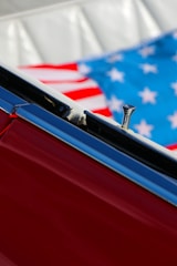 Close-up of a red car interior showing part of the door and an American flag in the background.
