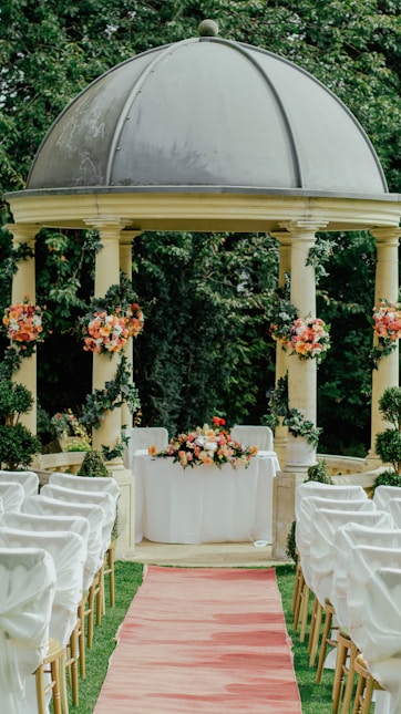 Gazébo beige et gris décoré pour un mariage avec des fleurs