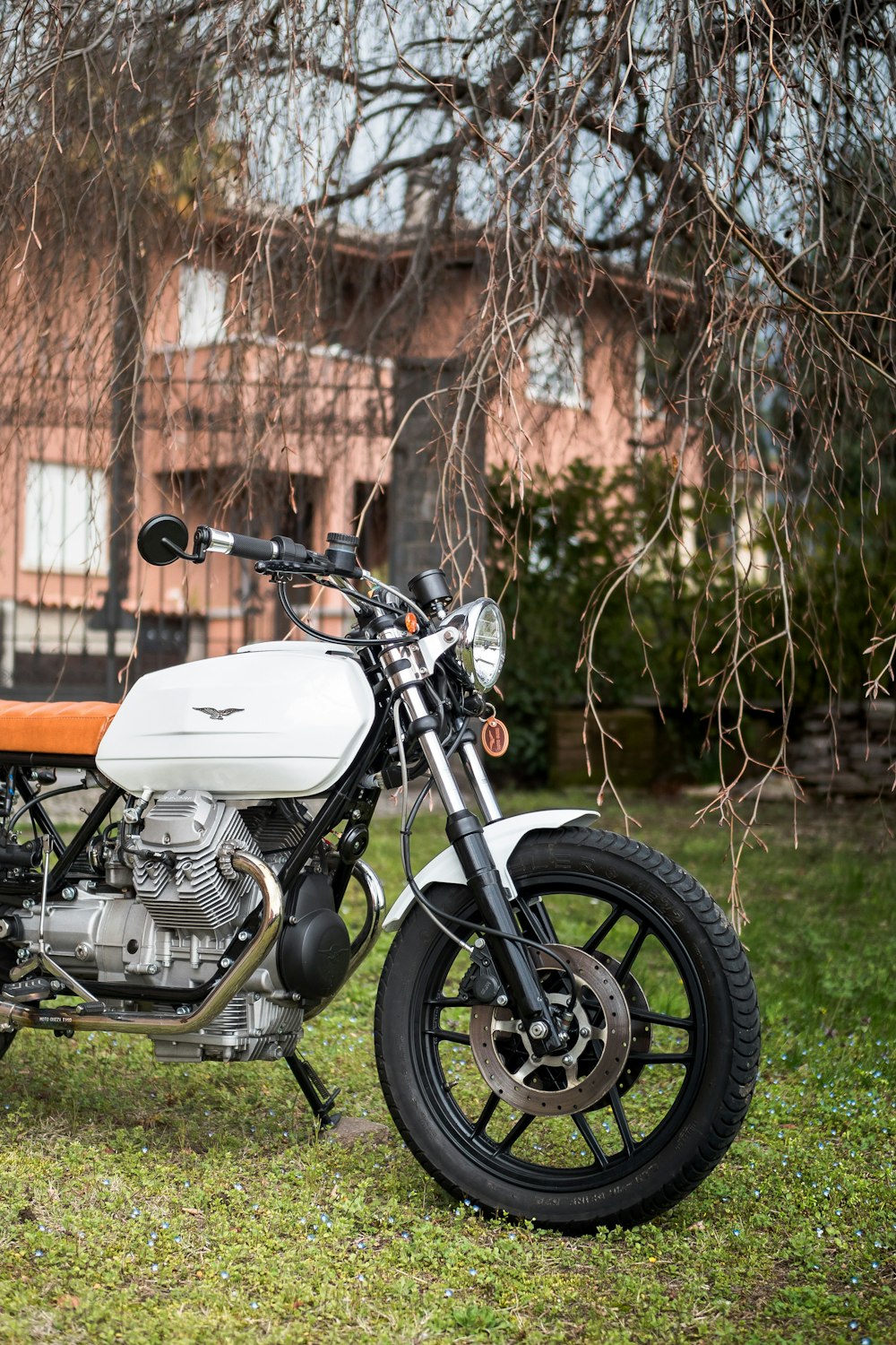 white motorcycle parking near house ]