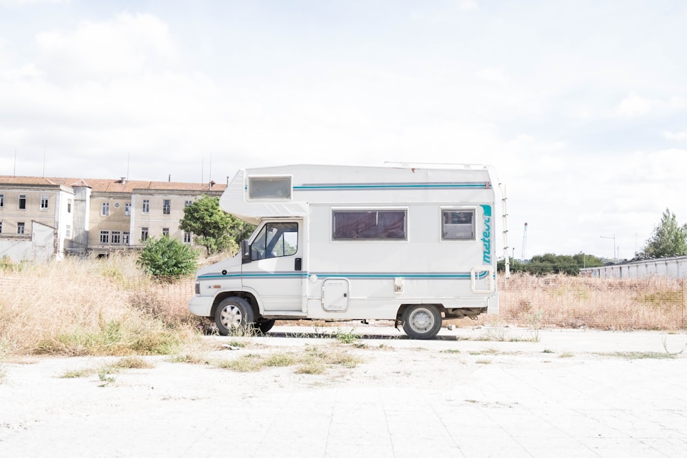 white and blue recreational vehicle parked near grass