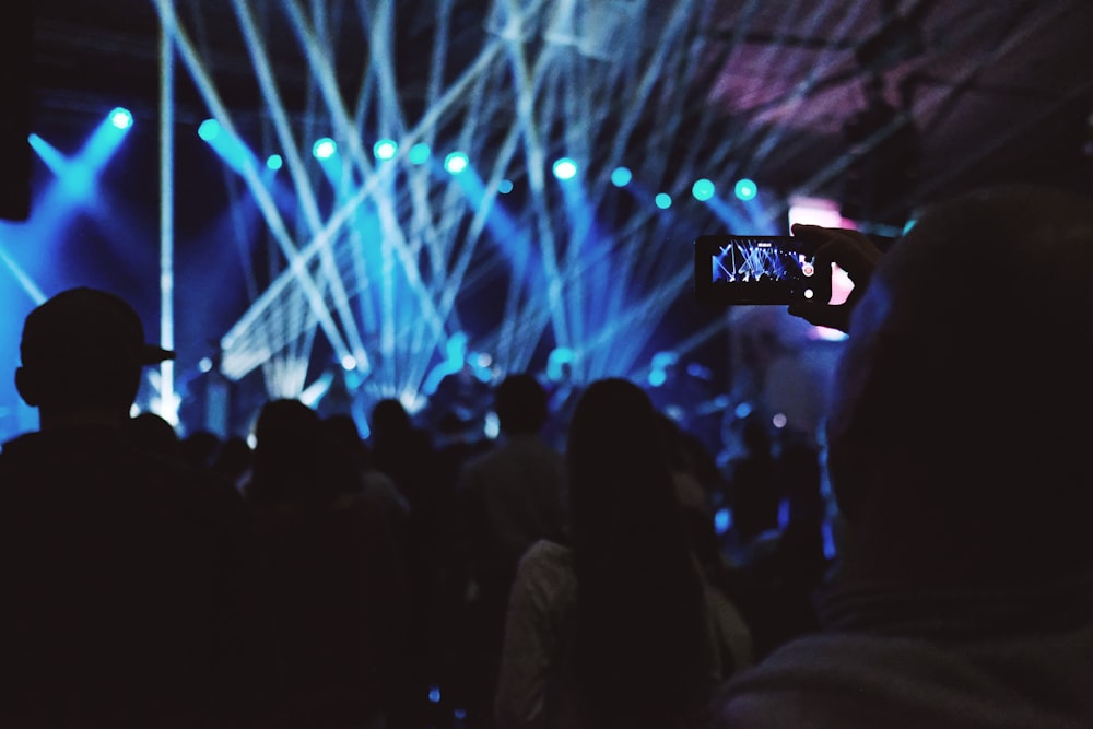 man taking video of concert inside building