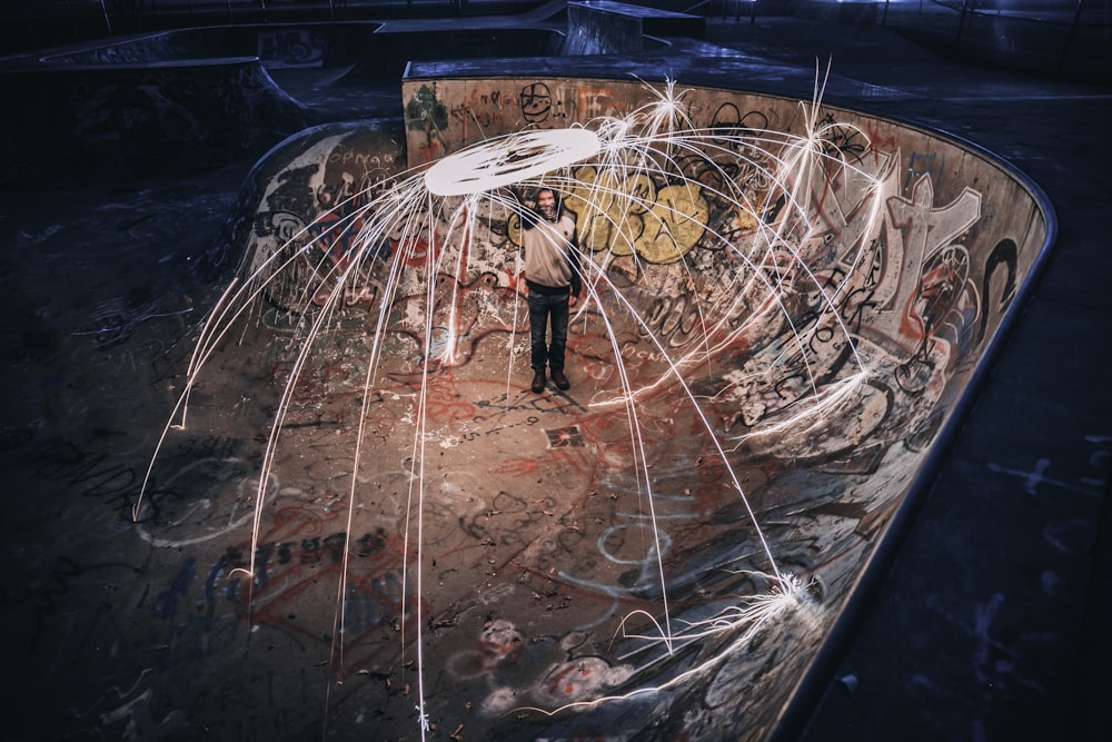 steel wool photography of man standing on skateboard half pipe ramp