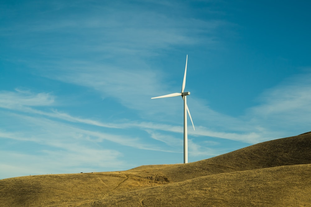 Molino de viento blanco en la colina durante el día