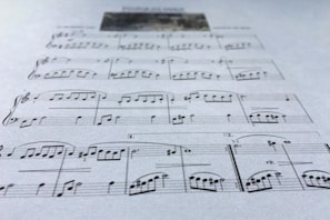 A close-up of a musician composing music with sheet notes and a laptop.