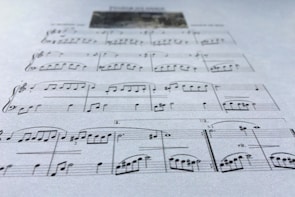 A close-up view of a sheet of music displaying various musical notes and symbols, written in a traditional style on a plain background. The focus is on the arrangement of notes and the linear staff, conveying a sense of musical composition.