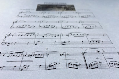 A close-up view of a sheet of music displaying various musical notes and symbols, written in a traditional style on a plain background. The focus is on the arrangement of notes and the linear staff, conveying a sense of musical composition.