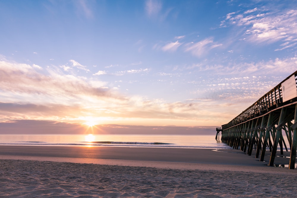 Fotografía de la silueta del muelle de madera negro cerca de la costa durante la salida del sol