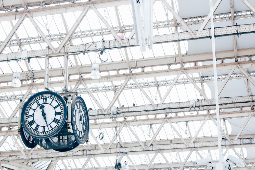 round white and blue analog hanging clock under white trusses