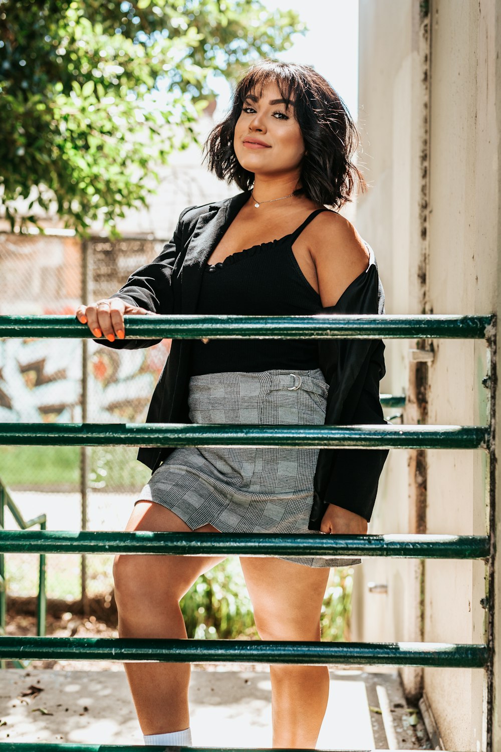 woman in black spaghetti strap top and grey skirt holding on handrail