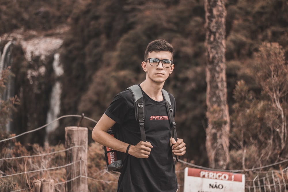 man wearing black framed eyeglasses standing near tree