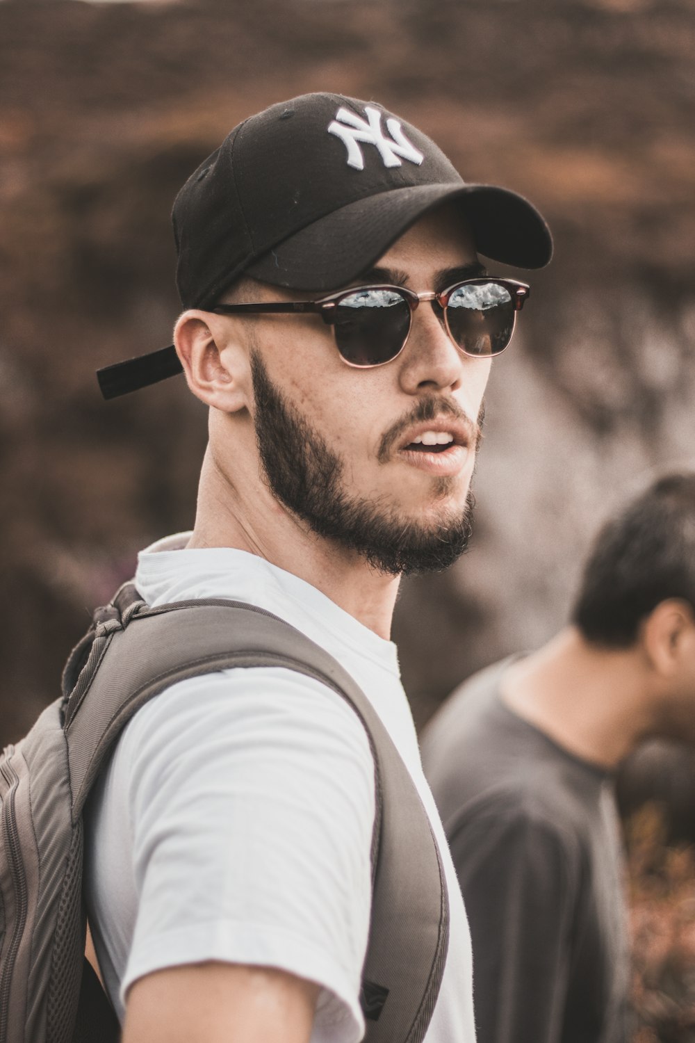 man wearing black fitted cap and white crew-neck shirt beside man