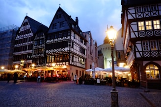 Charming European café terrace with vintage lanterns and quaint architecture at dusk.