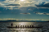 A group of paddlers setting out at dawn, their kayaks lined up along a shimmering lake.