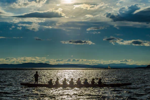 A group of paddlers setting out at dawn, their kayaks lined up along a shimmering lake.