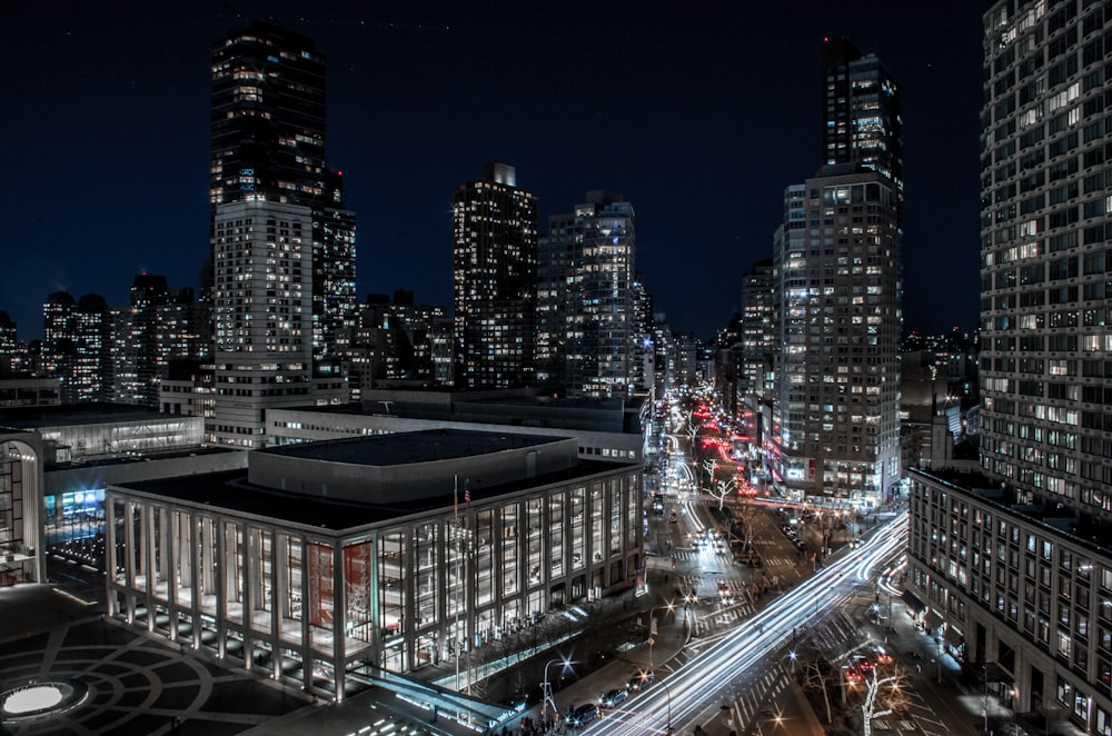 time lapse photography of vehicles near high-rise buildings at night time