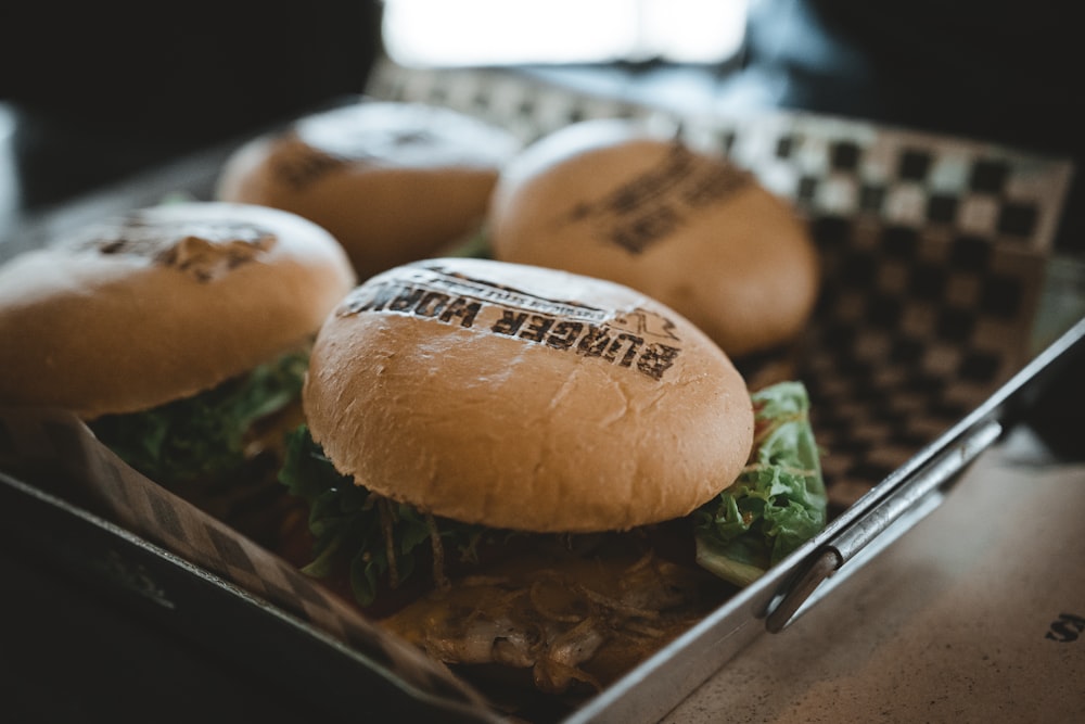 four burgers on gray steel pan