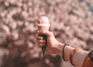 shallow focus photography of person holding ice cream