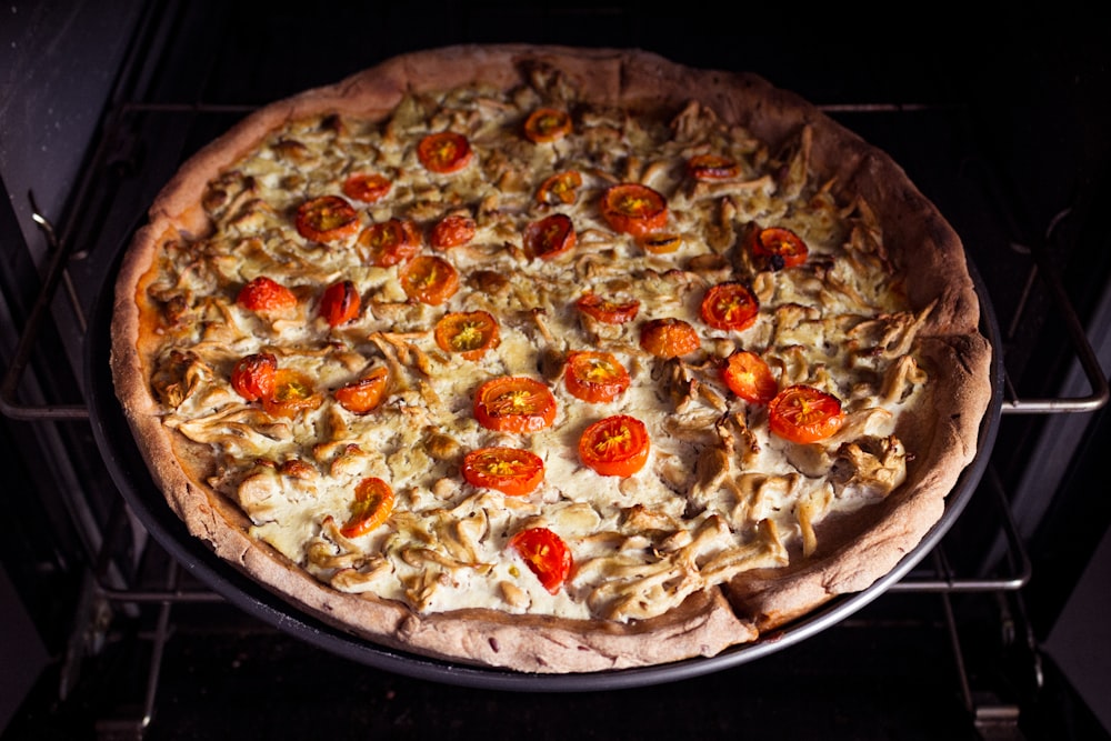photo of pizza with tomatoes in oven