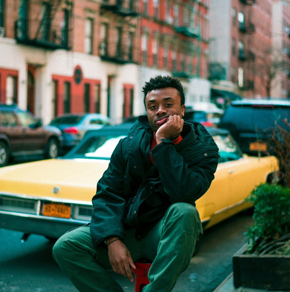 man sitting on red fire hydrant near yellow coupe