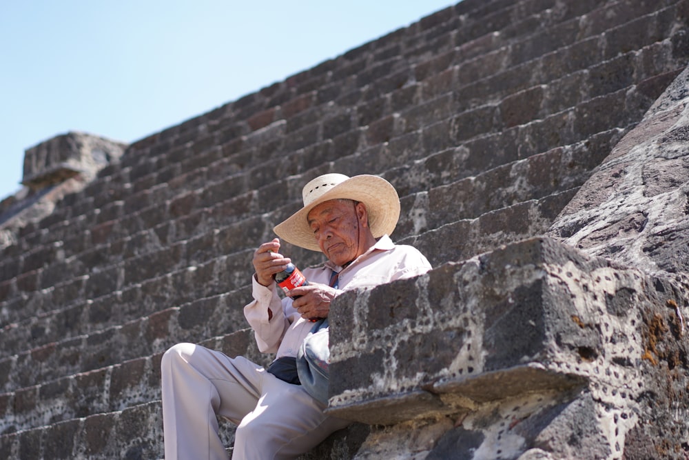 Hombre sentado en una escalera de hormigón sosteniendo una botella de refresco