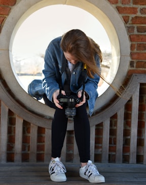 woman in blue denim button-up jacket sitting on round window