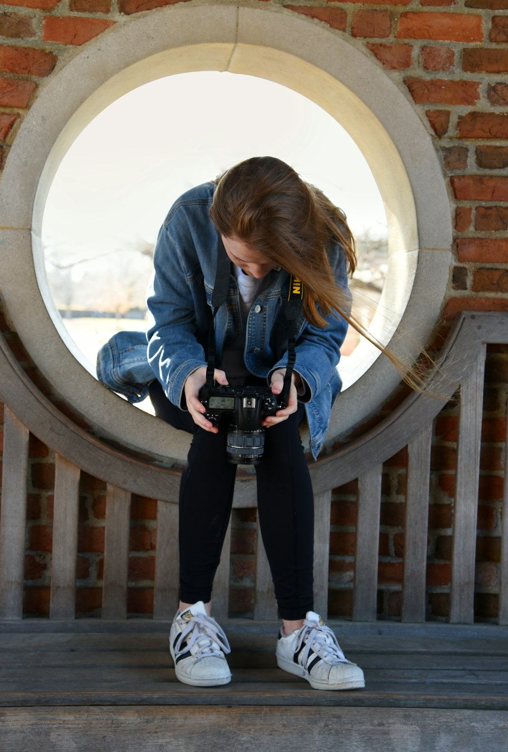 woman in blue denim button-up jacket sitting on round window