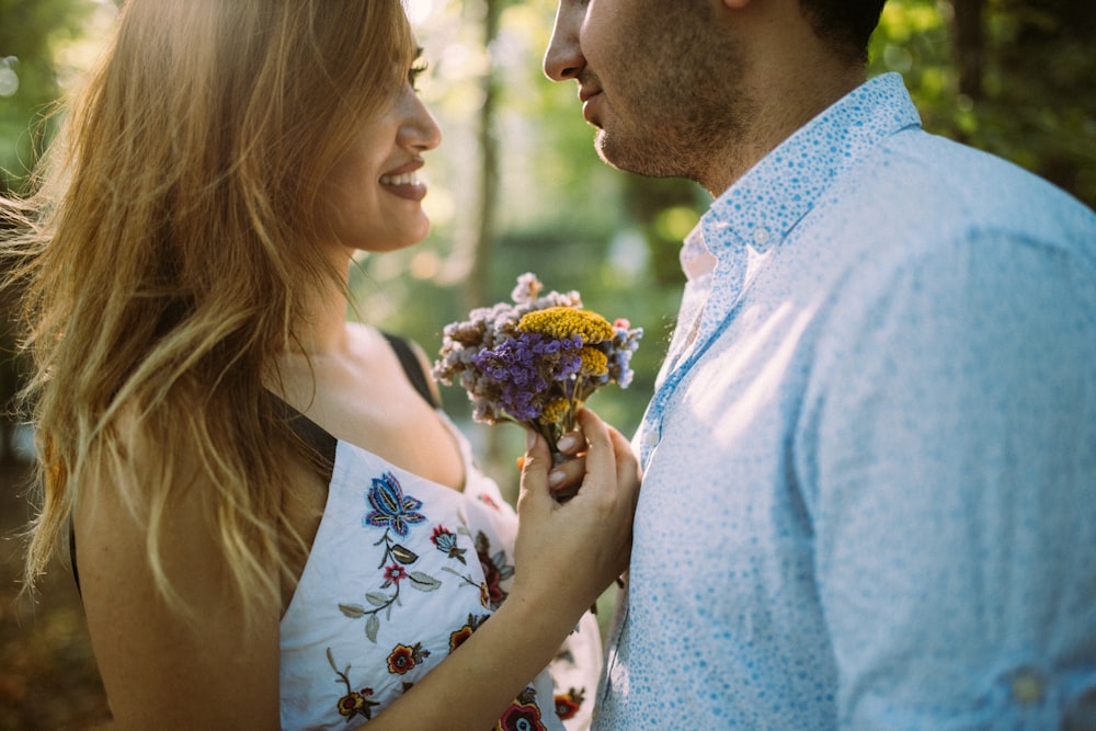 Mann und Frau stehen sich gegenüber, während sie Blumen halten