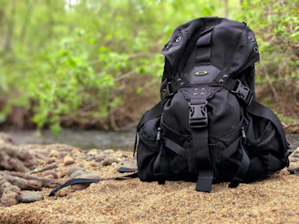 Close-up of a vintage backpack resting against a sandy dune with soft shadows.
