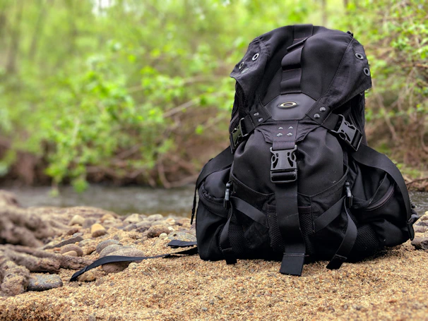 Close-up of a vintage backpack resting against a sandy dune with soft shadows.