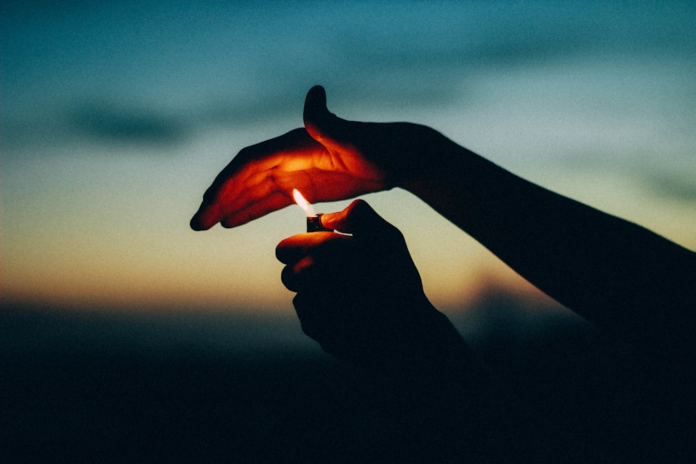 person lighted the lighter and cover with their hand