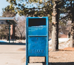 blue U.S. mail box on concrete pavement