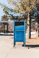 blue U.S. mail box on concrete pavement