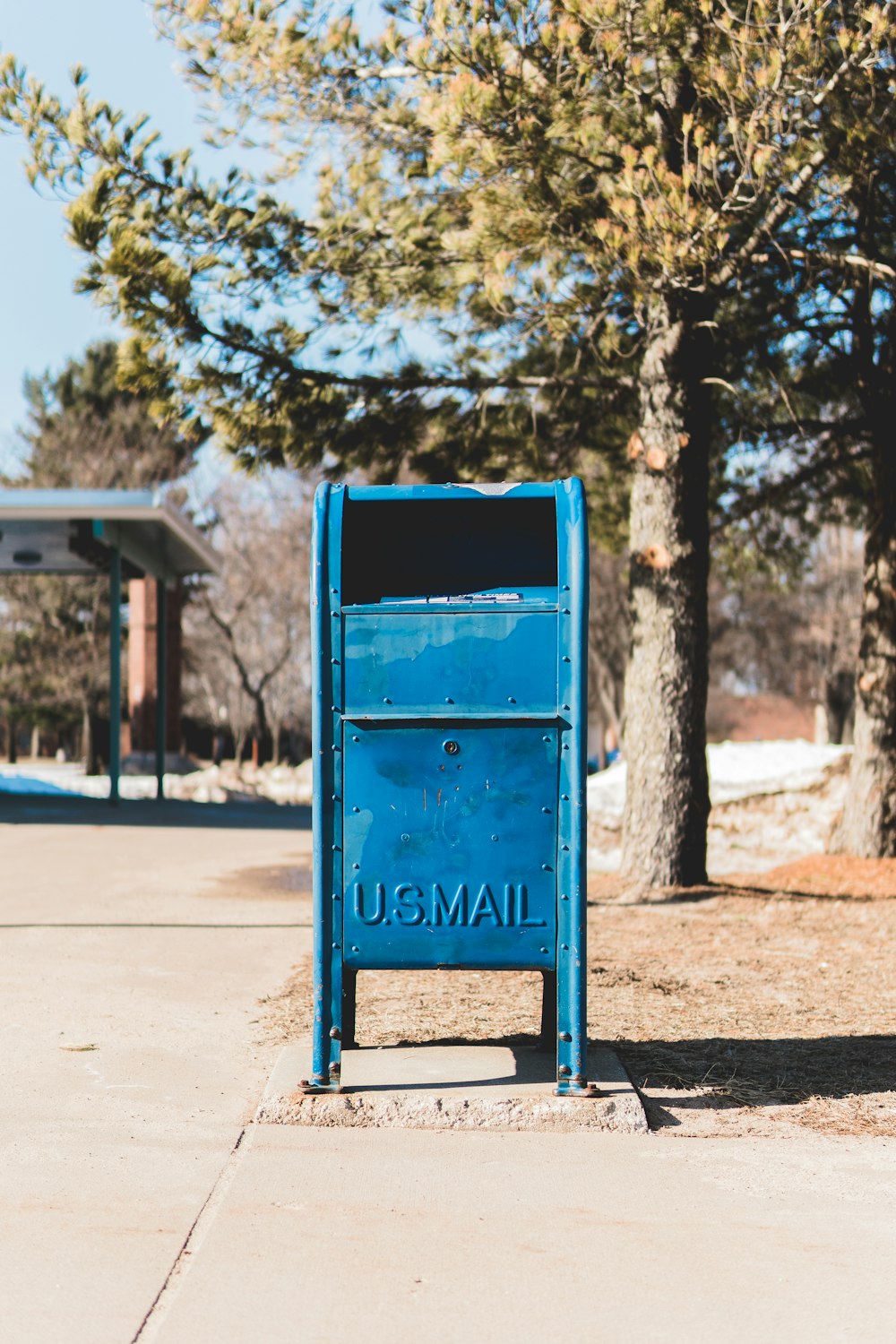 blue U.S. mail box on concrete pavement