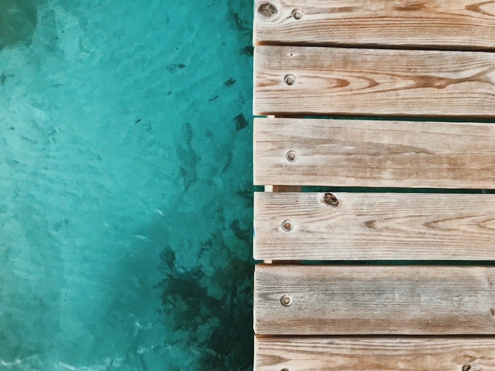 Un primer plano de un muelle de madera con agua de fondo