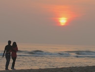 A couple enjoying a romantic dinner on the beach at sunset.