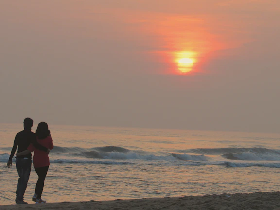 A smiling Latino couple enjoying a sunset walk on a Caribbean beach.