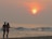 A happy couple enjoying a sunset dinner at the beach.