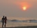 A happy couple enjoying a sunset dinner at the beach.