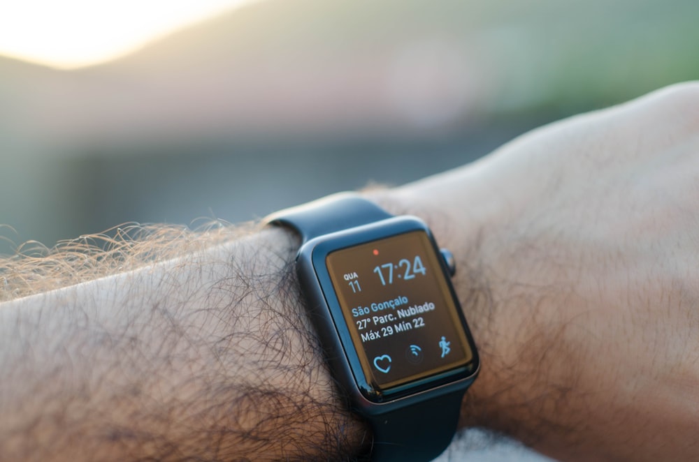 person wearing black smartwatch with black band